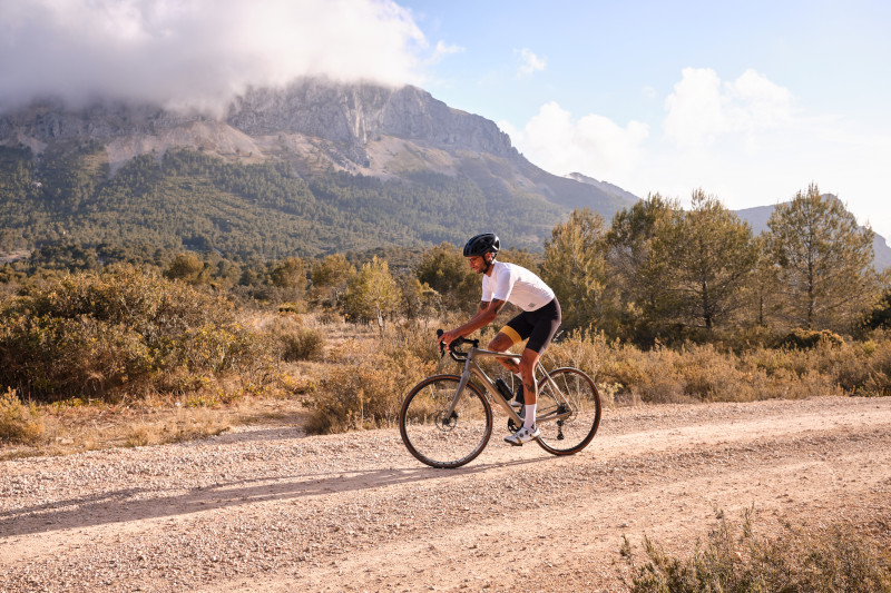 Mann fährt mit einem Gravelbike auf einem Kiesweg