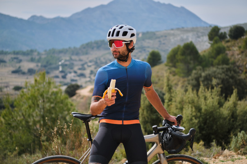 Ein Mann auf einer Fahrradtour isst eine Banane